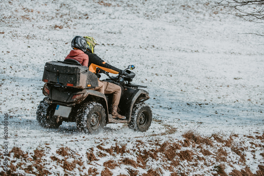 A young adventurous couple embraces the joy of love and thrill as they ride an ATV Quad through the snowy mountainous terrain