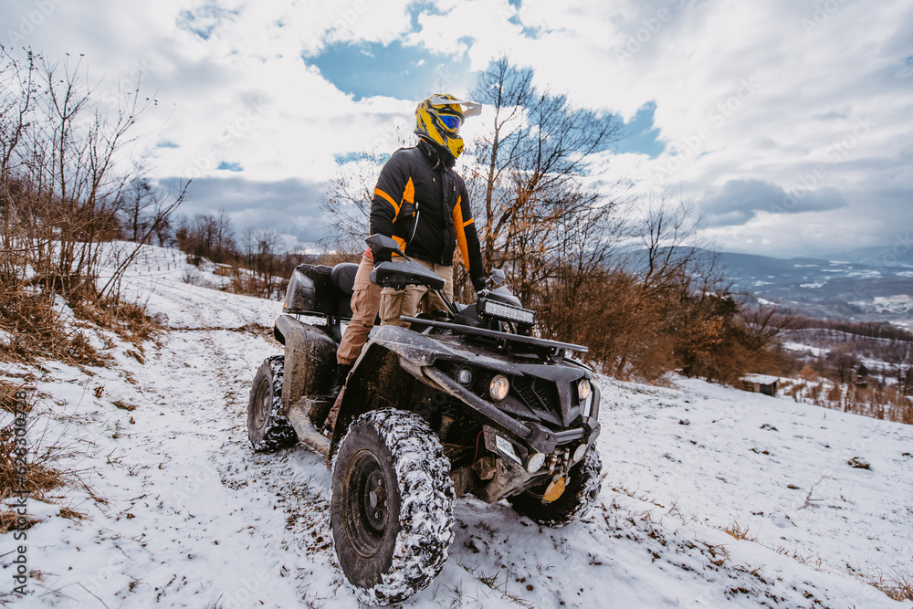 A young adventurous couple embraces the joy of love and thrill as they ride an ATV Quad through the snowy mountainous terrain