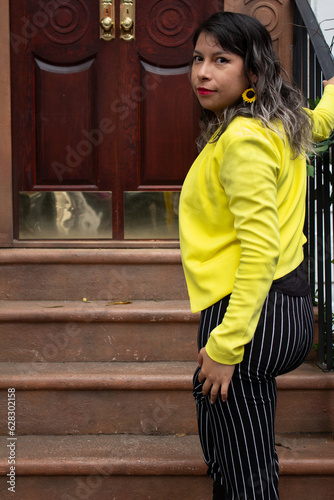 Mujer subiendo escaleras con saco amarillo y pantalón negro a rayas photo