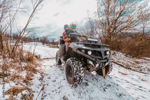 A young adventurous couple embraces the joy of love and thrill as they ride an ATV Quad through the snowy mountainous terrain