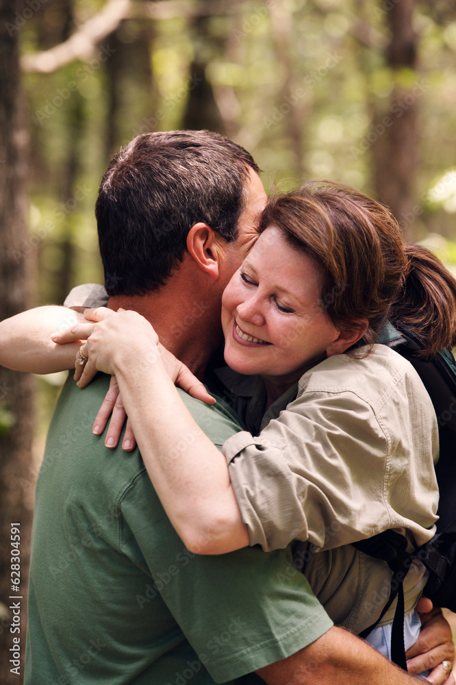 Older couple embracing while hiking on trail through the woods Older couple embracing while hiking on trail through the woods