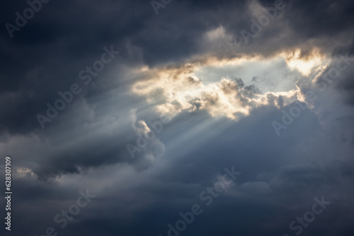 Light rays burst through cloud opening.