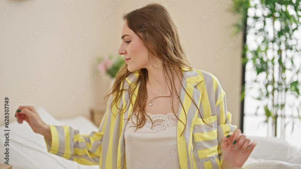 Young blonde woman waking up holding smartphone at bedroom Young blonde woman waking up holding smartphone at bedroom