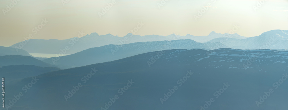 View over nordic mountain peaks in Norway from a hike up Hauknestinden, Hauknes, Mo i Rana, Helgeland, Norway. High peaks in a fjord landscape, snow covered. Clear Norwegian summer skies. Wild Norway	 - obrazy, fototapety, plakaty 