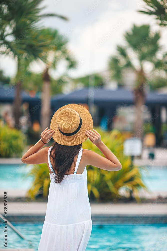 Young beautiful woman enjoying summer vacation in infinity luxury swimming pool