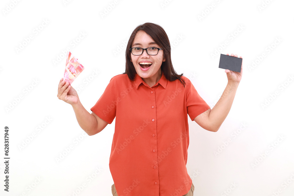 Excited asian woman holding a blank mock up card while carrying Indonesia banknotes Excited asian woman holding a blank mock up card while carrying Indonesia banknotes