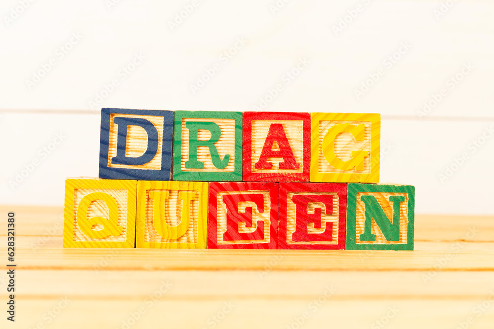 Spectacular colorful letters on wooden cubes on a wooden board with the word drag queen.