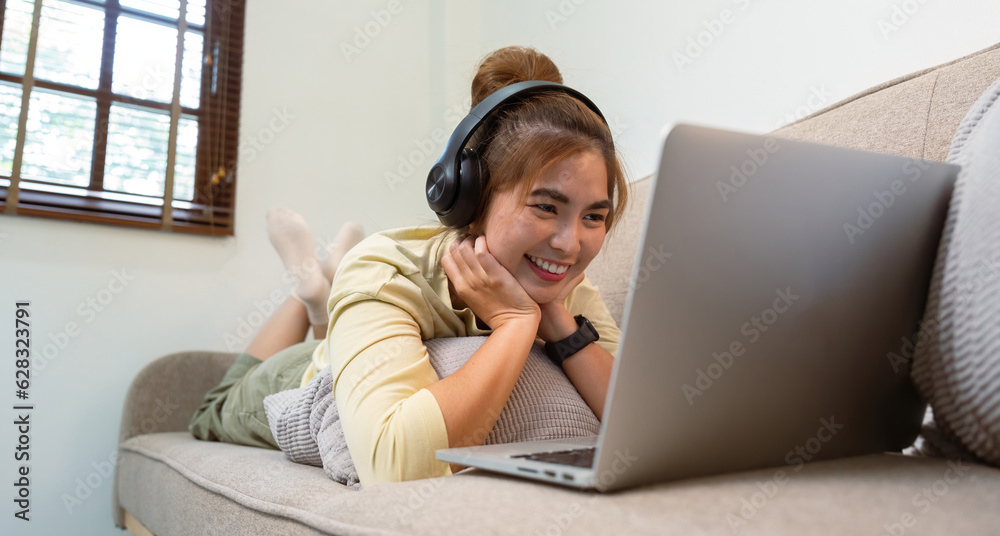 Concept of relaxation at home, Happy Asian woman watching online movie via laptop in living room