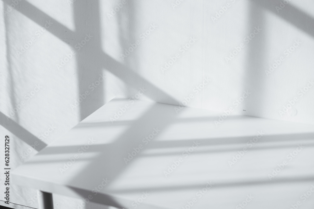 Obraz premium Empty tabletop with window shadow on concrete wall texture background, suitable for product presentation backdrop.