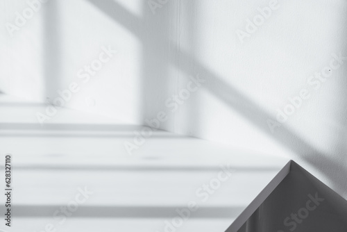 Empty tabletop with window shadow on concrete wall texture background, suitable for product presentation backdrop.