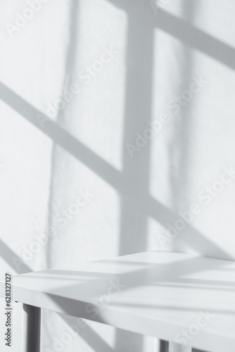 Empty tabletop with window shadow on concrete wall texture background  suitable for product presentation backdrop.
