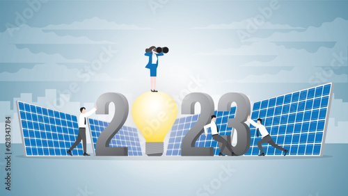Vision businesswoman use binocular on 2023 light bulb powered by solar cells with team support. ESG, Renewable, Alternative, Green energy, Sustainable Environmental policy, Net zero, Carbon reduction.