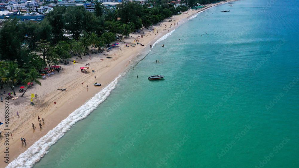 Aerial view of clear sea water with boats and tourists enjoying the beach in Patong beach, Phuket island, Thailand.