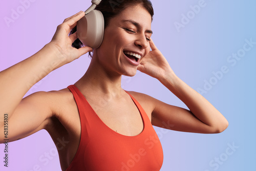 Cheerful sportswoman listening to music in headphones