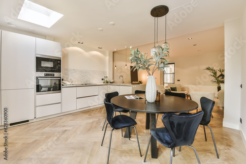 Bilde på lerret a kitchen and dining area in a house with white walls, wood flooring and an open