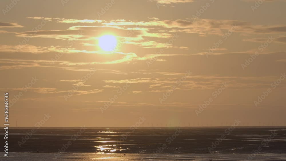Golden sun moving down behind cloud at sunset with wind farm on horizon. Time lapse 30x. Sony FX30. Golden sun moving down behind cloud at sunset with wind farm on horizon. Time lapse 30x. Sony FX30.