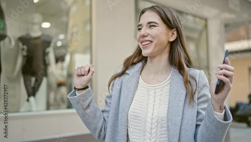 Young hispanic woman dancing listening to music on smartphone at street