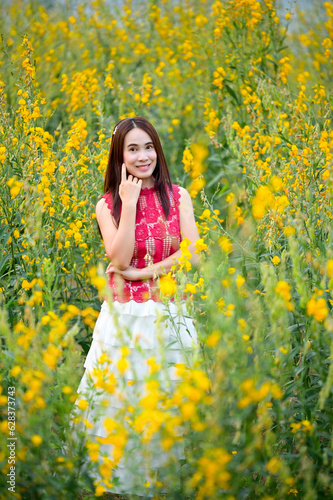 Asian woman standing among yellow flowers © Sitthipong