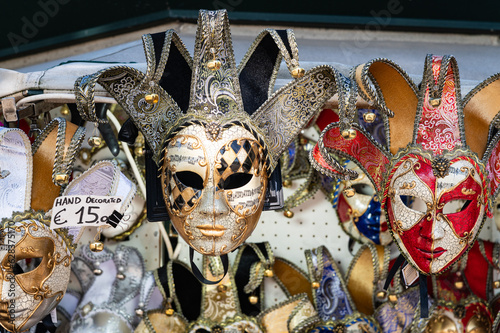 Photo of a a selection of carnival masks including an ornate gold and silver musical one for sale for 15 Euros at a street vendor stand in Venice, Italy.