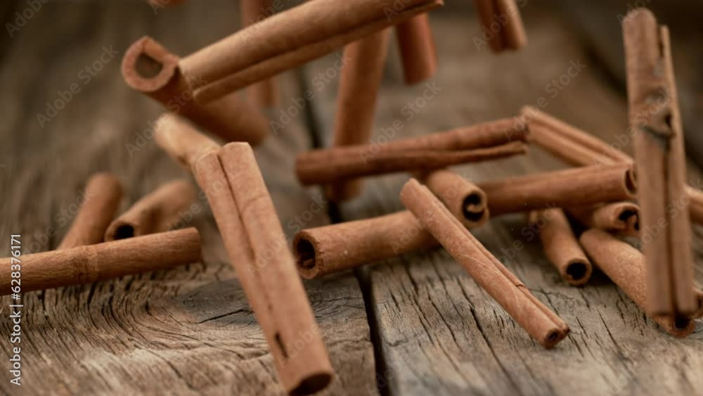 Cinnamon sticks falling on wood in slow motion