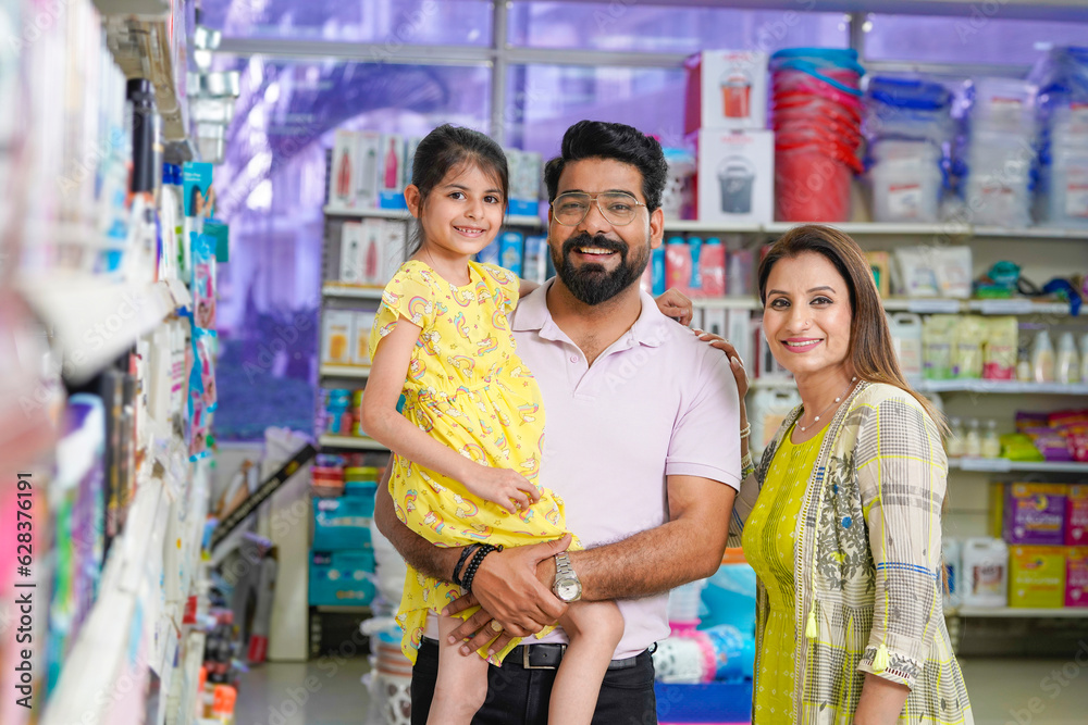 Fototapeta premium Happy indian couple standing with his daughter at grocery shop.
