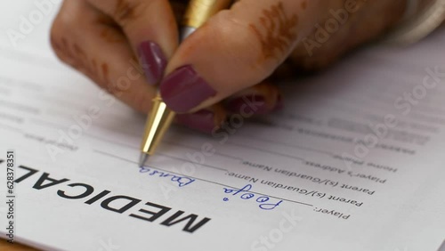 Closeup shot of a female signing medical indemnification form. A young Indian woman filling a form - medical insurance / medical loan  healthcare and medical photo