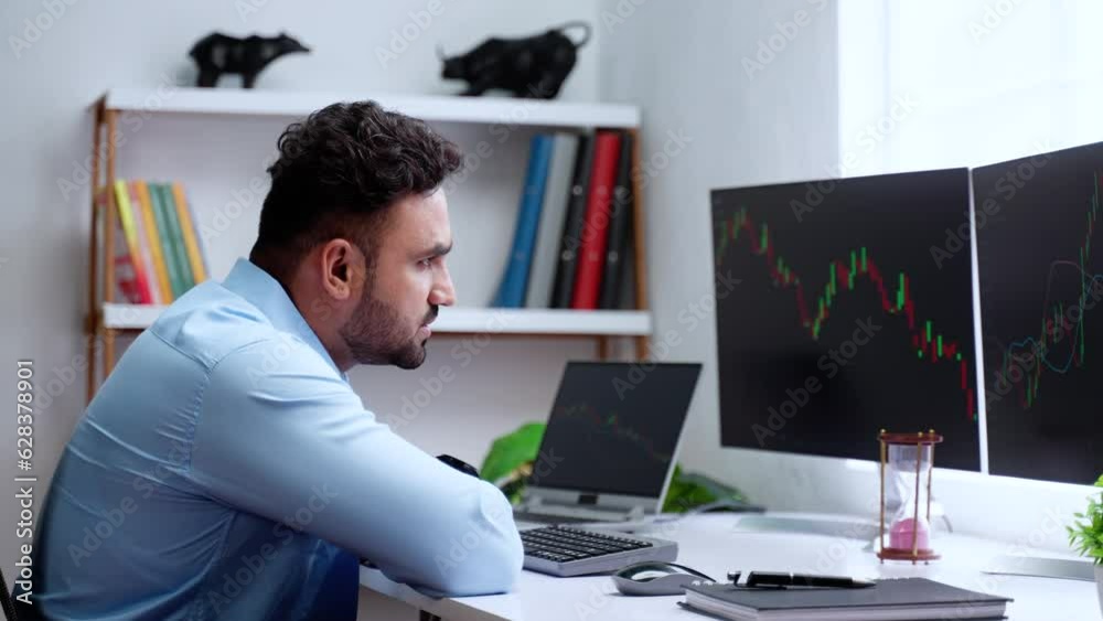 Worried or lost indian trader watching stock market graph on monitor at office after trading - concept of Economic Downturn, Investment Stress and Market Turmoil