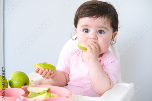 Foto baby eating apple sitting in a high chair. weaning