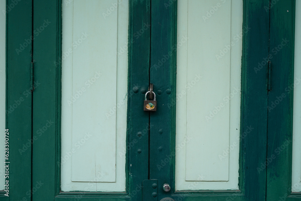 The door of an ancient house is made of wooden panels connected to hinges, painted in green. The door of an ancient house is made of wooden panels connected to hinges, painted in green.