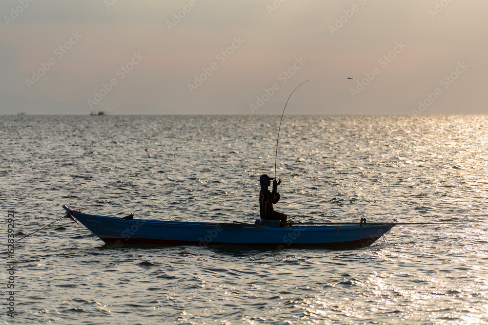 Silhouette of thai fisherman in a boat on the sea water at beautiful ...