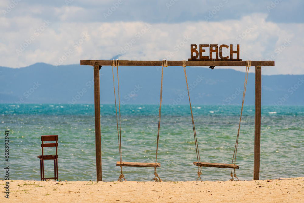 Wooden two swings and chair on peaceful beach background on tropical island of Koh Phangan, Thailand, relax by the sea, summer holiday destination Wooden two swings and chair on peaceful beach background on tropical island of Koh Phangan, Thailand, relax by the sea, summer holiday destination