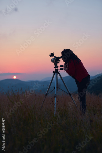 Female astronomer looking at the sun with a telescope.