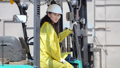 Black-haired woman sits in excavator for trash transporting at big waste sorting plant. Female manager checks durability of apparatus in factory