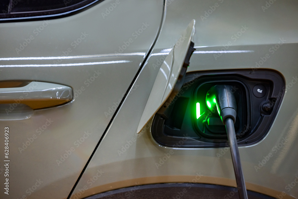 Fototapeta premium EV charging an electric car.Power supply for electric car charging. Socket for electric car battery charger. EV car charging station. Nature energy, Clean energy, Green eco concept. Plugging in cable.
