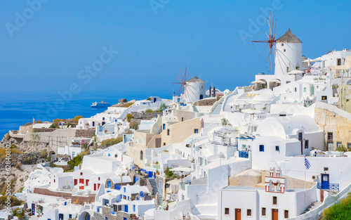Fototapeta Naklejka Na Ścianę i Meble -  Oia Santorini Greece on a sunny day during summer with whitewashed homes and churches, Greek Island Aegean Cyclades on a sunny day with blue ocean