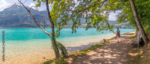path along the lake Wolfgangsee, tree avenue on the shore, Zwolferhorn mountain in the background, Sankt Gilgen, Austria photo