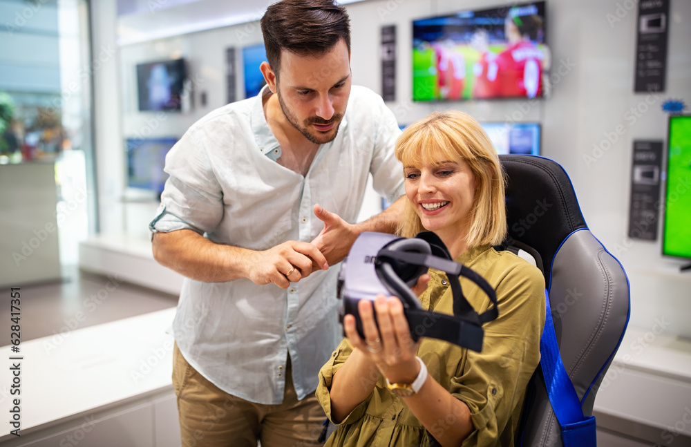 Couple enjoying with VR goggles at tech store. Shopping couple having fun at marketplace. Couple enjoying with VR goggles at tech store. Shopping couple having fun at marketplace.