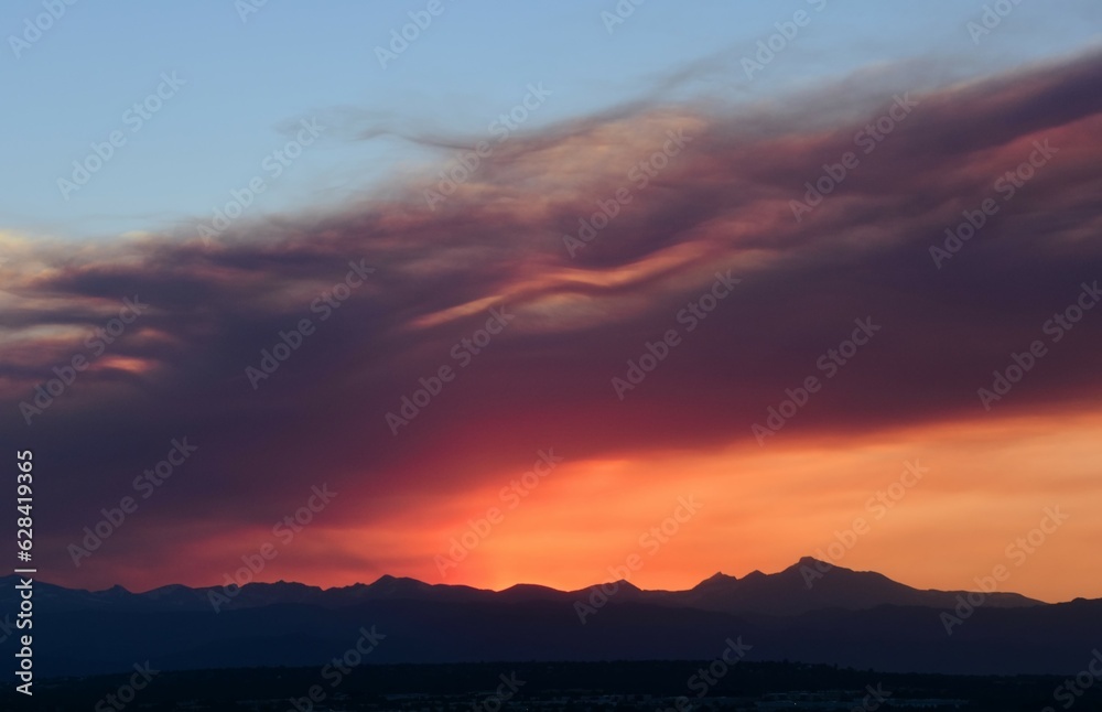 colorful sunset over long's peak and the front range of the rocky mountains through the smoky haze of the spring creek wildfires near parachute, as seen from broomfield, colorado