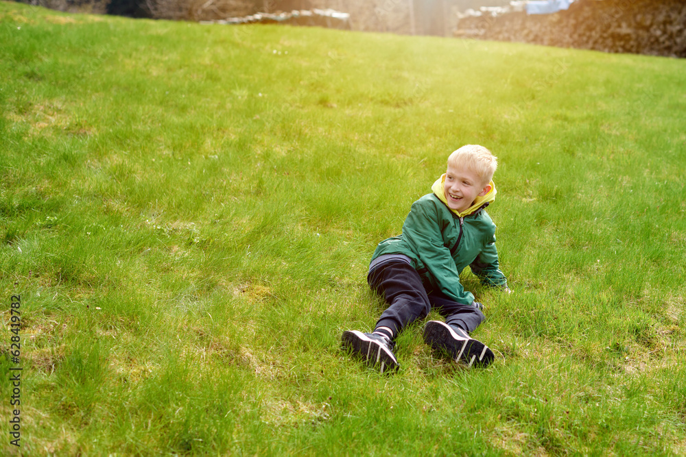 Fun teenager sits on hillside. Boy resting in mountains. School boy sitting of hill in grass field and enjoying beautiful landscape view. Rear view of teenage boy hiker resting in nature. Active Fun teenager sits on hillside. Boy resting in mountains. School boy sitting of hill in grass field and enjoying beautiful landscape view. Rear view of teenage boy hiker resting in nature. Active
