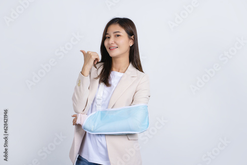 Beautiful Asian girl with broken arm  she is smiling happily over white background  health concept  accident  insurance  life insurance  health  hospital
