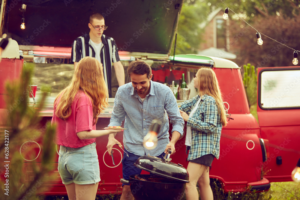 Group of young people, friends spending time outdoors, having barbecue party, cooking, drinking cocktails, talking. Countryside meeting. Concept of friendship, leisure time, weekends, summer, party Group of young people, friends spending time outdoors, having barbecue party, cooking, drinking cocktails, talking. Countryside meeting. Concept of friendship, leisure time, weekends, summer, party