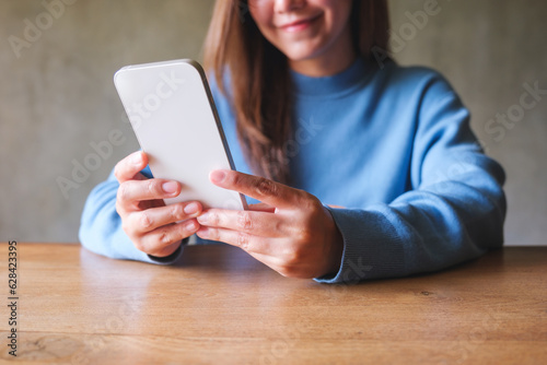 Closeup image of a young woman holding and using mobile phone