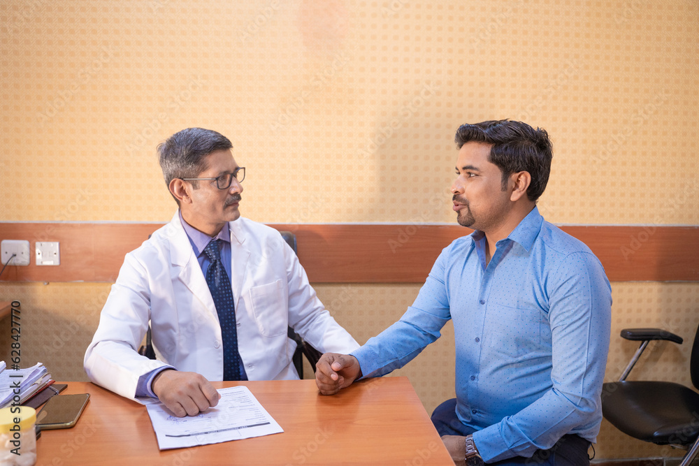 Indian male doctor talking with patient at clinic. Indian male doctor talking with patient at clinic.