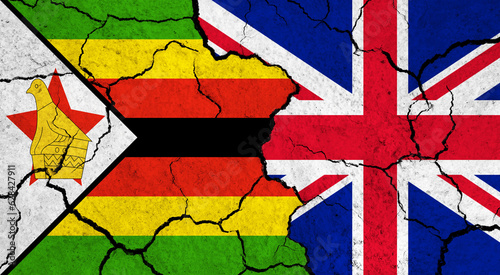 Flags of Zimbabwe and United Kingdom on cracked surface - politics, relationship concept