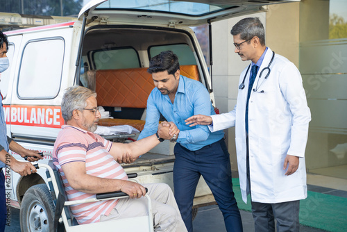 Doctor receiving old man from ambulance and checking while moaning in pain.