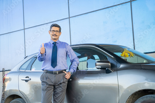 Indian corporate man standing with his car at out of office and showing thumps up. © PRASANNAPIX