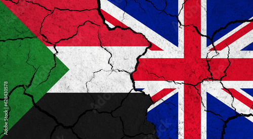 Flags of Sudan and United Kingdom on cracked surface - politics, relationship concept