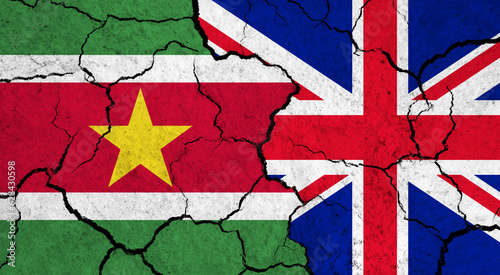 Flags of Suriname and United Kingdom on cracked surface - politics, relationship concept