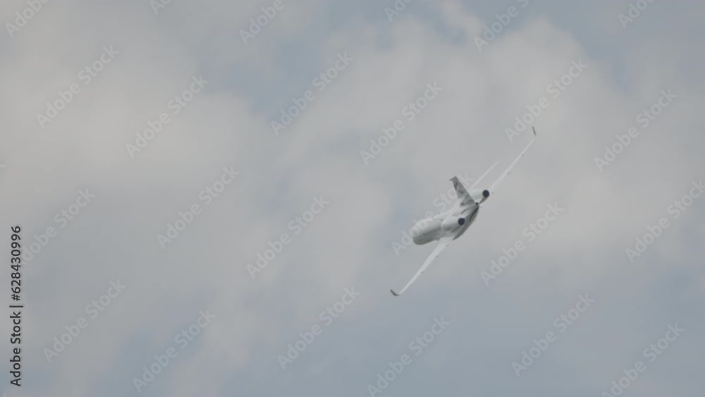 Large white private business Jet during flight under blue sky with clouds