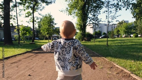 Baby takes first steps. Baby boy running in the park. Happy childish dream concept in park. Single baby child walking single along the path in the park. Kid run in nature in park 4k